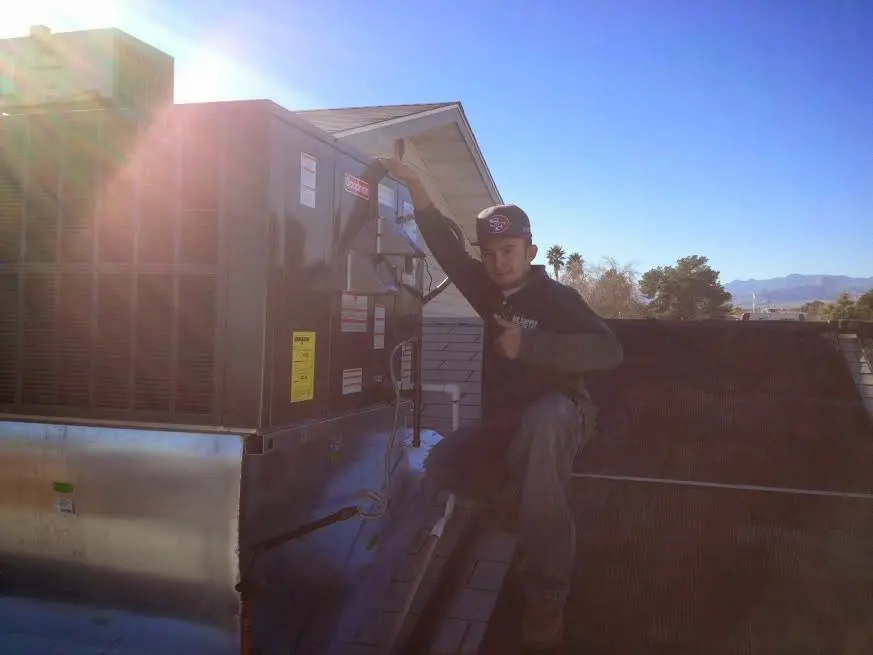 HVAC technician performing AC Tune-Up on a rooftop unit in River Ridge